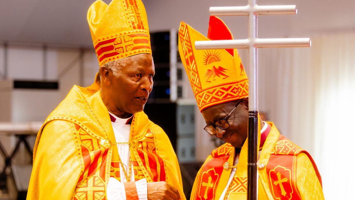 Myr Dr.  Mbanda Arkiyepiskopi ucyuye igihe ashyikiriza inkoni ya gishumba Arkiyepiskopi mushya w'Itorero Angilikani mu Rwanda Myr Dr. Gahima